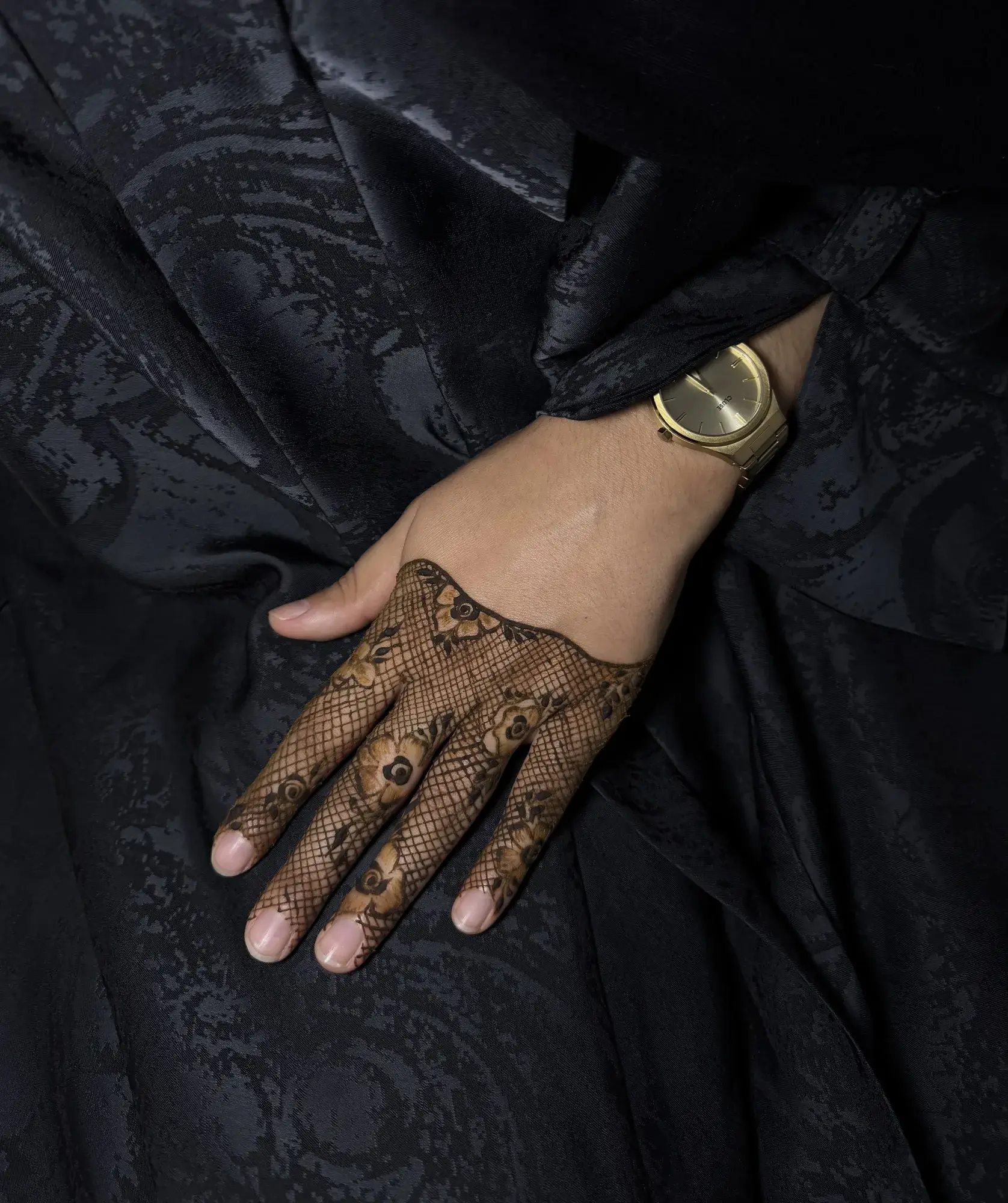 Henné façon dentelle sur une main posée sur de la soie noire